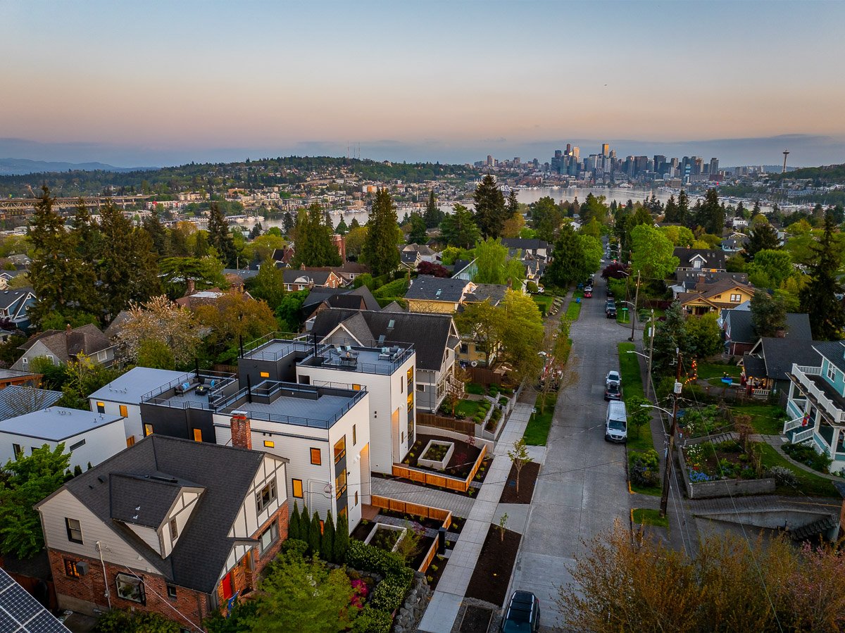 Professional aerial real estate photography of a Seattle neighborhood at dusk with downtown skyline views, Lake Union, and the Space Needle in the distance.