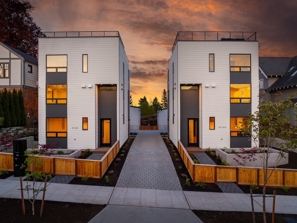 Professional real estate photography of modern Seattle townhomes at dusk with rooftop decks, contemporary architecture, warm interior lighting, and dramatic sunset skies.