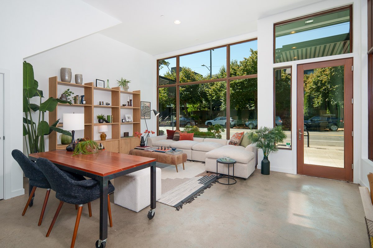 Professional real estate photography of a modern Seattle live-work commercial space with floor-to-ceiling windows, open living area, and street-level access.