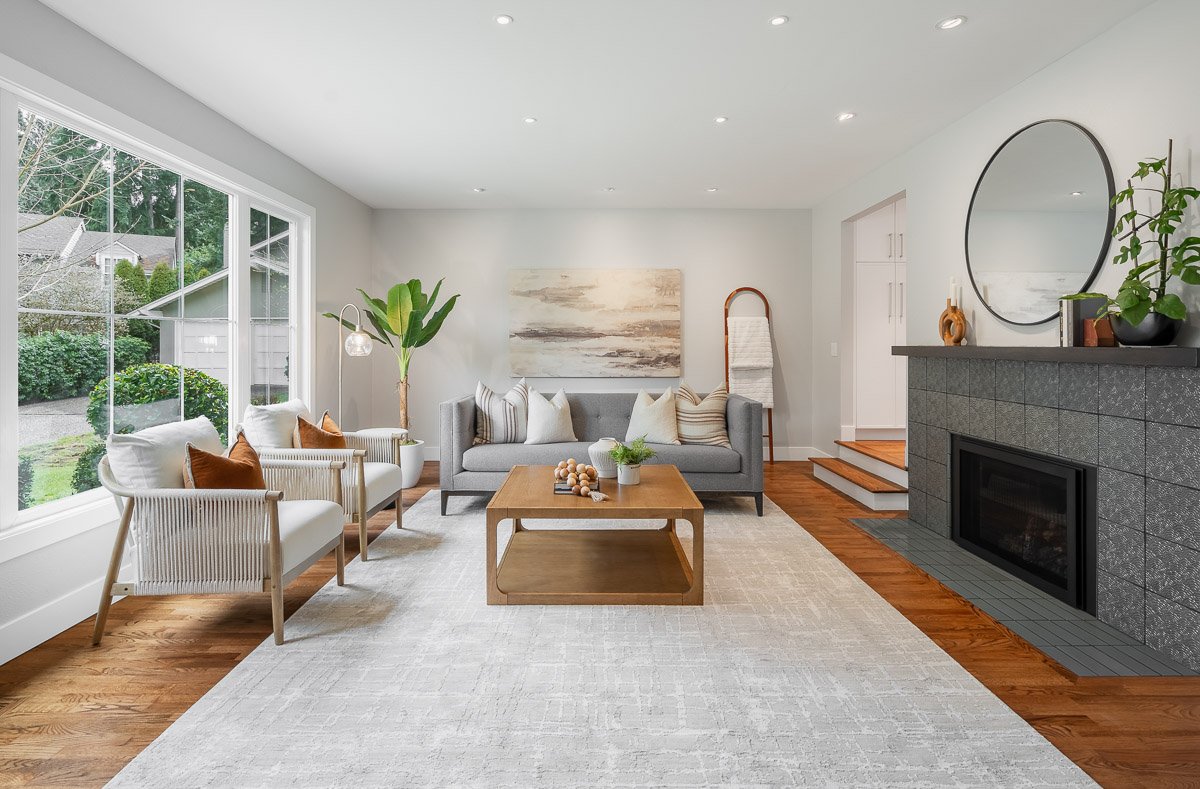 Professional real estate photography of a bright Seattle living room with modern staging, large windows, hardwood floors, and a contemporary fireplace.