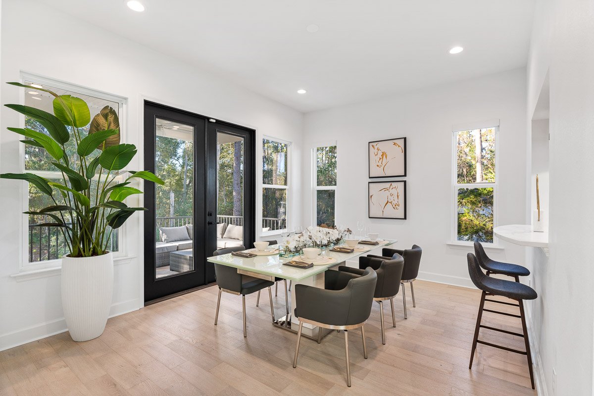 Professional real estate photography of a bright Seattle dining room with modern furnishings, large windows, French doors, and abundant natural light.