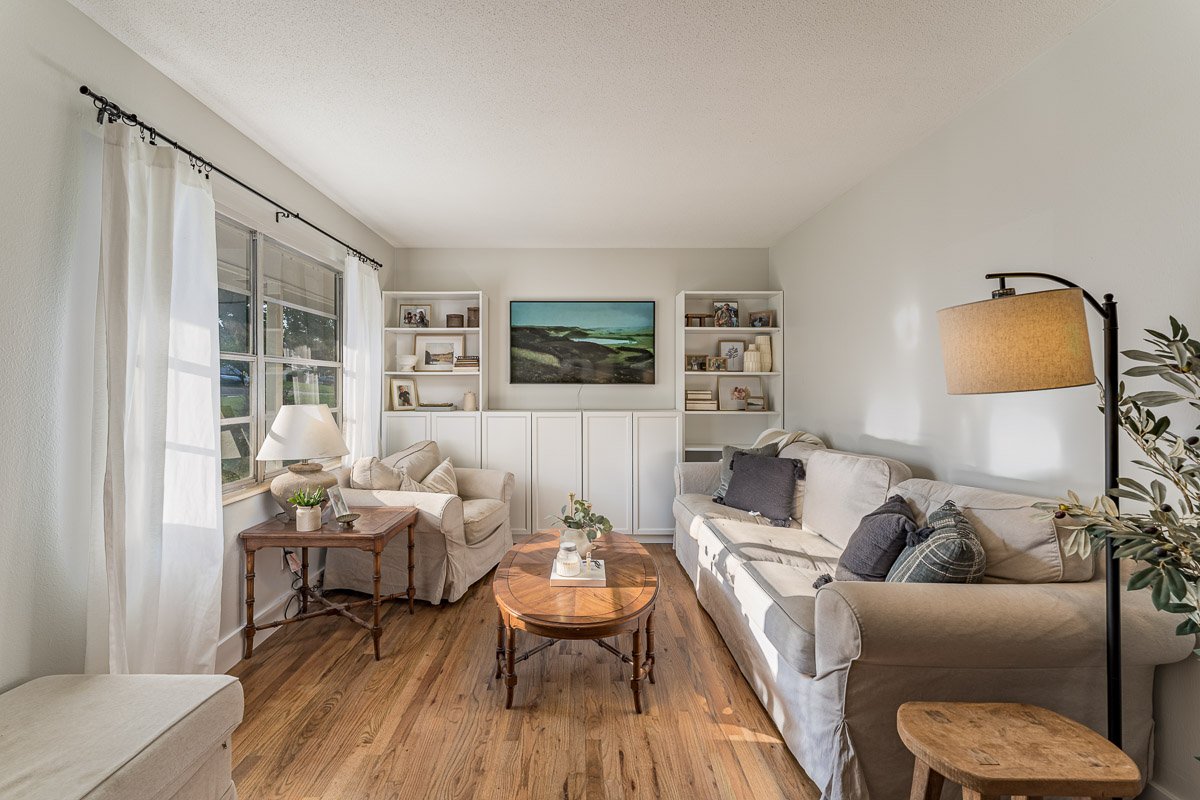 Professional real estate photography of a bright Seattle living room with hardwood floors, built-in shelving, neutral furnishings, and abundant natural light.